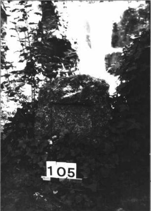 Grabstein 105 (Index: 100085531) Zustand: Schriftplatte auf Vorderseite entfernt Maße HxBxT: 50x45x24 cm Beschreibung: grob stelenhaft behauener Stein, rechteckige Schriftplatten: Grabstein 105