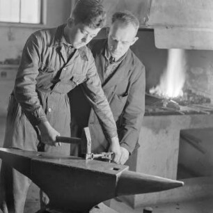 Lehrling von Borgward beim Schmieden am Amboss mit Hammer und Zange