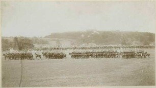 Ulanen in Uniform mit Mütze zu Pferd mit Standarten in Reih und Glied im Gelände reitend