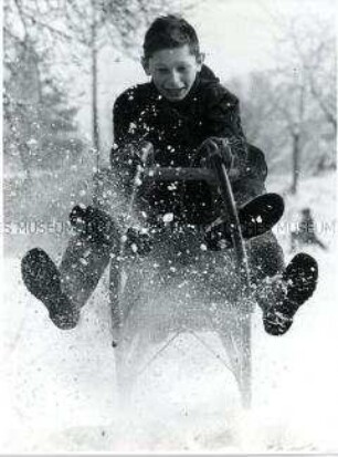 Zwei Jungen auf einem Schlitten im Schnee (Altersgruppe 18-21)