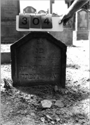 Grabstein 304 (Index: 99797855) Material: Sandstein, weiß Zustand: leicht verwittert Maße HxBxT: 45x43x11 cm Beschreibung: Stele, giebelartiger abgeflachter Abschluß, Sockel: Grabstein 304