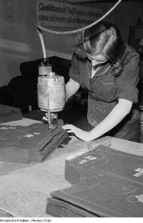 Portrait einer Frau beim industriellen Zuschneiden von Stoff im VEB Bekleidungswerk Leipzig