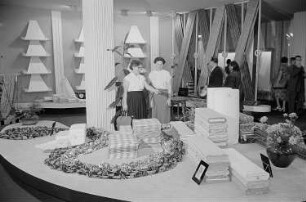 Besucher der Leipziger Herbstmesse 1955 betrachten ausgestellte Stoffballen