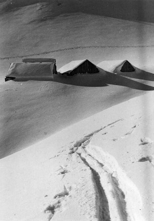 Winterbilder. Hütten im tiefen Schnee. Im Vordergrund Skispuren