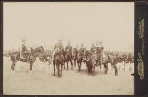 Berittene Uniformierte im Gespräch, im Hintergrund Infanterie.