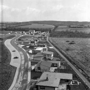 Im Hölk: Einfamilienwohnhäuser, dahinter die Eisenbahnstrecke Richtung Neumünster, im Hintergrund der Stadtforst Kneeden: Blick nach Westen