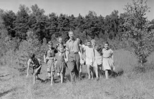 Ferienlager am Teufelssee : Kindergruppe mit einem Betreuer über eine Wiese laufend