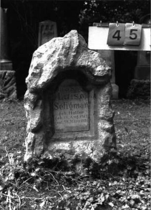 Grabstein 45 (Index: 100101467) Material: Kalkstein, weiße Marmorplatte Zustand: gut Maße HxBxT: 88x46x37 cm Beschreibung: Stele, rustica, Schriftplatte mit rund eingezogenem Rundbogenabschluß Steinmetz: Fugazza: Grabstein 45