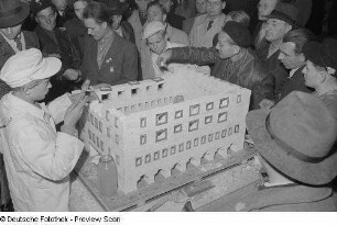 Besucher an einem Messestand während des Anfertigen eines Architekturmodells
