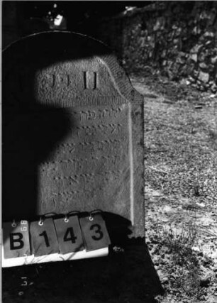 Grabstein 143 (Index: 99798047) Material: Sandstein, rot Zustand: stark verwittert Maße HxBxT: 705x0x11 cm Beschreibung: Stele, geschweifter Abschluß: Grabstein 143B