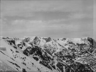 Bergpanorama : Eine Berglandschaft mit verschneiten Gebirgszügen im Hintergrund. Im Vordergrund sitzen drei Mitglieder des Transkontinentalen Geographenkongresses