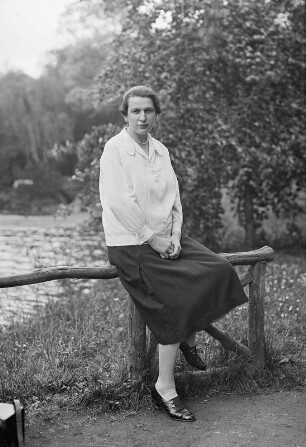 Portrait einer Frau, am Geländer eines Gewässers sitzend