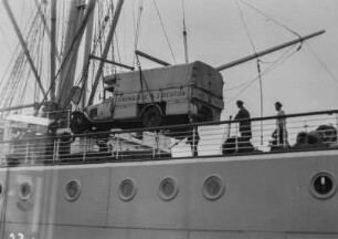 Verladen der Lastwagen : Ein Lastwagen wird mit einem Kran an Bord eines Schiffes geladen