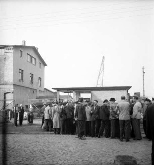Kampnagel AG: Kampstraße: Eisengießerei: Außenaufnahme: Streik: streikende Arbeiter stehen Schlange vor Pförtnerhaus: links Männer an Werkstor: links Werksgebäude: hinten Kran