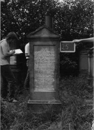 Grabstein 25 (Index: 99753458) Material: Sandstein Zustand: verwittert Maße HxBxT: 160x56x30 cm Beschreibung: Stele, getreppter Sockel, Giebel, eingetieftes Schriftfeld rechteckig: Grabstein 25