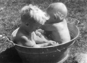 Kinderbilder. Zwei Kleinkinder in einer Zinkwanne auf einer Wiese