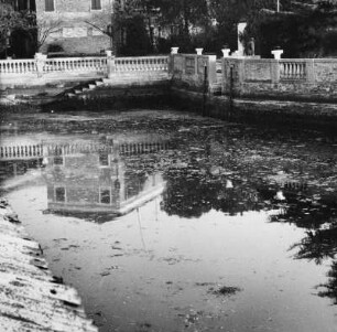 Architekturspiegelung in einem Teich, umgeben von Steinmauer