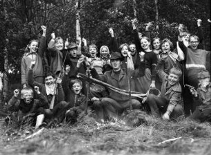 Gruppe Gerhard Klass : Gruppenbild von Kindern und ihrem Erzieher im Wald. Alle tragen Jäger- und Jagdsachen bzw. "Cowboy und Indianer"-Sachen
