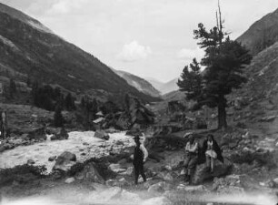 Bergsteiger : Drei Bergsteiger pausieren an einem Fluss, hinter ihnen Baumgrenze