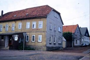 Dorfgaststätte an Straßenkreuzung; Häuser entlang der Straße