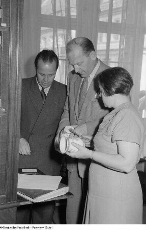 Drei Personen in einem Verkaufsgespräch über Porzellanvasen, Herbstmesse 1953