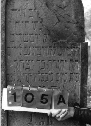 Grabstein 105 (Index: 100116415) Material: Sandstein Zustand: rechter oberer Teil der Stele abgebrochen mit Textverlust Maße HxBxT: 165x56x25 cm Beschreibung: aufgesockelte Stele mit Rundbogenabschluß, eingetieftem Schriftfeld und Schriftfeld am Sockel: Grabstein 105A (Nachholaufnahme)