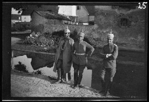 3 Offiziere mit Pickelhaube vor einem Dorfteich mit der Ortskirche im Hintergrund