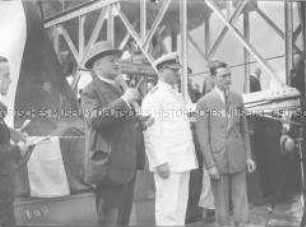 Kapitän Leopold Ziegenbein mit James Fitzmaurice und einer dritten Person an Bord des Hochseepassagierdampfers "Bremen", rechts die Katapultanlage für das Postflugzeug