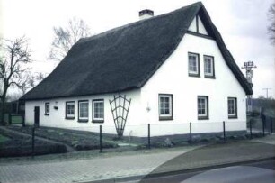 Reinfelder Straße 2: giebelständiges Fachwerkhaus mit Reetdach: Straßenfront Wohntrakt: Traufseite, links Wirtschaftstrakt mit Stalltür