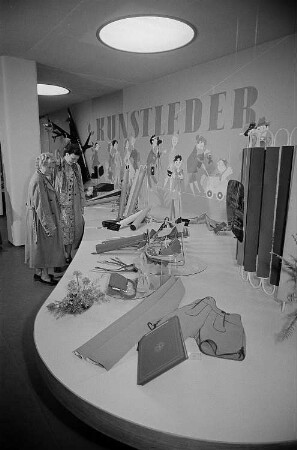 Zwei Besucherinnen der Leipziger Herbstmesse 1955 sehen sich ausgestellte Gegenstände aus Kunstleder an