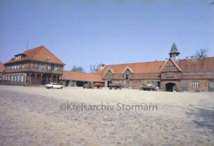 ehemaliges Gut Trenthorst-Wulmenau: Trenthorst: Wirtschaftshof [Karree]: Blick von Südosten: links westlicher Kopfbau mit Arkaden, rechts Torhaus mit Uhrturm und Durchfahrt