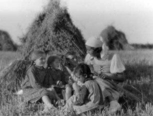 Junge Frau mit Kindern, auf einem Stoppelfeld sitzend