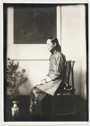 Portrait einer jungen chinesischen Frau auf einem Stuhl sitzend