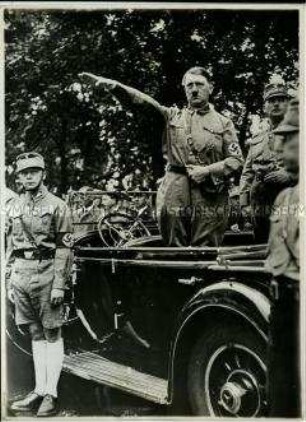 Adolf Hitler grüßend im offenen Wagen stehend