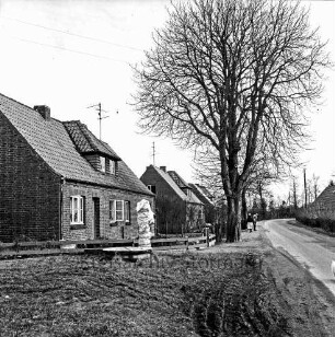 Schulenburg: Pölitzer Straße: Gut: links Siedlungshäuser mit Vorgärten und Bäumen: davor eine eingepackte Wasserpumpe: hinten rechts Mann und Frau