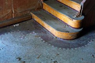 Am Markt (10): traufständiges Backsteingebäude mit umlaufendem Gesims: Innenansicht: Detailaufnahme Flur: Terrazzoboden mit Mosaikkante, Fuß von Treppe