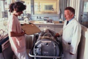 Arzt und Krankenschwester vor einem Kinderbett