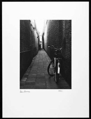 Holland. Fahrrad in einem schmalen Durchgang, an der Wand lehnend