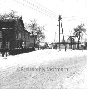 Rethwischdorf: Dorfplatz: Hauptstraße: Bundesstraße B 208 mit Kopfsteinpflaster: links Bäume: dahinter Bauerngehöft Spiering: rechts Strommast: dahinter Bauernhäuser: Winter