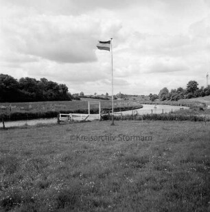 Trave: Bootsanleger unterhalb des Ortes: vorn Wiese mit Fahnenmast: im Hintergrund Knicklandschaft