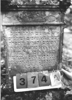 Grabstein 374 (Index: 99799680) Material: Sandstein Zustand: verwittert Maße HxBxT: 97x48x15 cm Beschreibung: Stele, Abdeckplatte mit Giebelaufsatz, Seitenakrotere, unter der Sima Friesband, Schriftfeld eingetieft, getreppter Sockel Symbolik: florale Elemente: Grabstein 374A