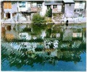 Häuserfassaden spiegeln sich in einem Fluss