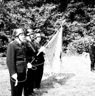 Kupfermühle: Amtsfeuerwehrfest: Präsentation der Fahne der Amtsfeuerwehr durch drei Feuerwehrmänner: dahinter Bäume