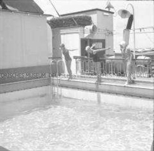 Drei Damen beim Sprung ins Schwimmbecken des Hochseepassagierdampfers "Columbus"
