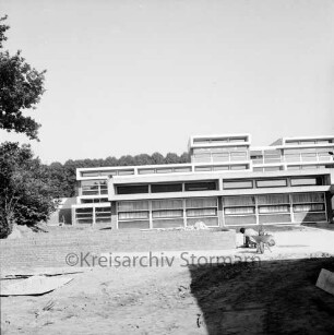 Grund- und Hauptschule Bargteheide-Land [früher Dörfergemeinschaftsschule, später Johannes-Gutenberg-Schule]: Alte Landstraße: Erweiterungsbau nach Fertigstellung: Außenansicht: Herrichten der Außenanlagen: Arbeiter mit Schubkarre