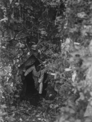 Mann in einer Höhle : Aufnahme eines Mannes, der aus einer Höhle steigt.