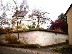 Ansicht von Westen mit Kirche (Langhaus mit Nordteil und Giebelseite im 19 Jh erneuert) über Kirchhofmauer (Wehrgang im 18 Jh abgetragen)