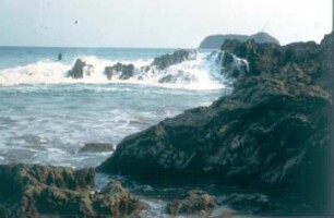 Costa Rica. An vorgelagerten Felsen bricht sich die Brandung