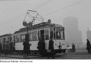 Eine Straßenbahn der Linie 29 Richtung Schkeuditz an einer Haltestelle am Karl-Marx-Platz, im Hintergrund das Europahaus