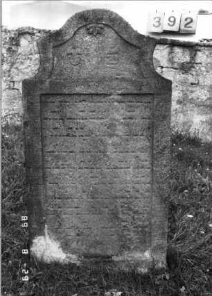 Grabstein 392 (Index: 100107876) Material: gelb-grauer Sandstein Zustand: stark verwittert und versalzen, weitgehender Textverlust Maße HxBxT: 143x77x14 cm Beschreibung: Stele, Abschluß Sonderform, Schriftfeld rechteckig eingetieft: Grabstein 392